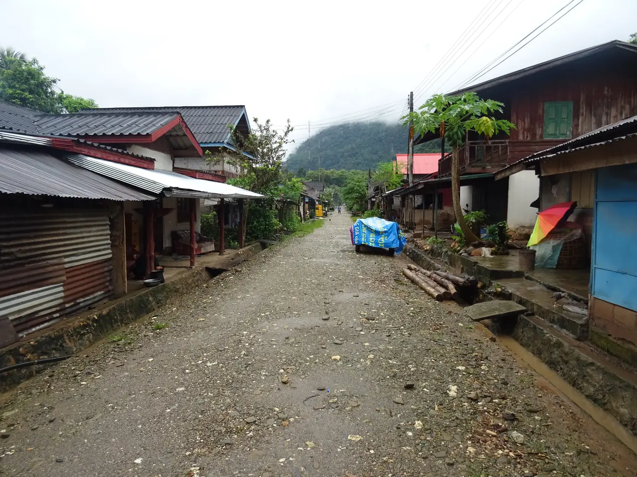 The unpaved main street of Muang Ngoi Neua lined with wooden shopfronts, with no cars in sight