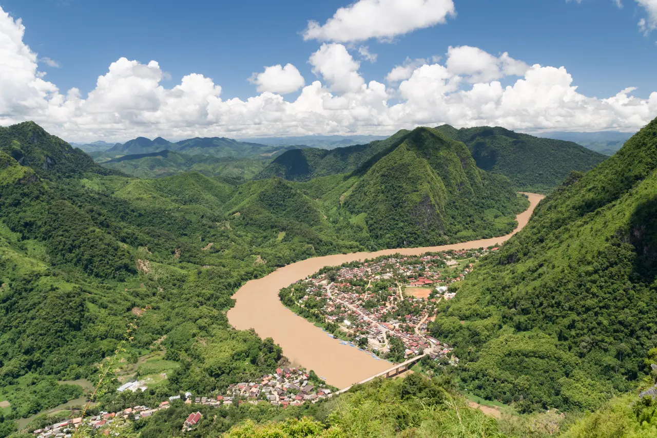 Green mountains rolling away from the Nam Ou valley, with the town of Nong Khiaw on the river bend