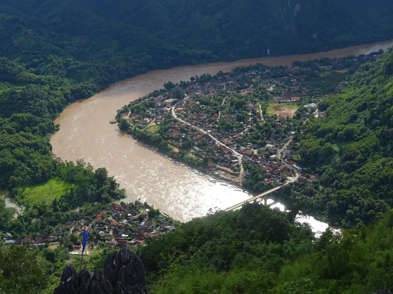 Nong Khiaw from above: the brown Nam Ou river curving around the town between steep forested mountains