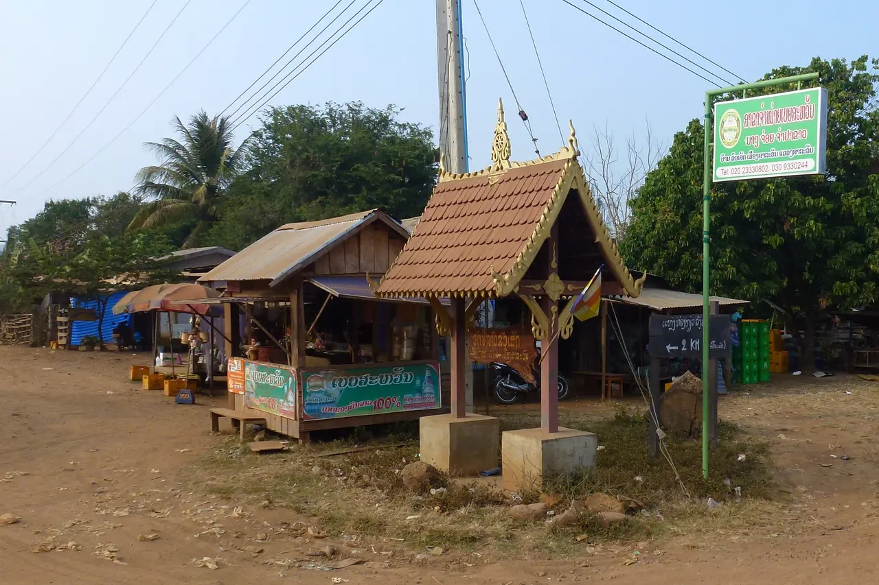 Small market stalls and a decorated pavilion beside the road in Paksong