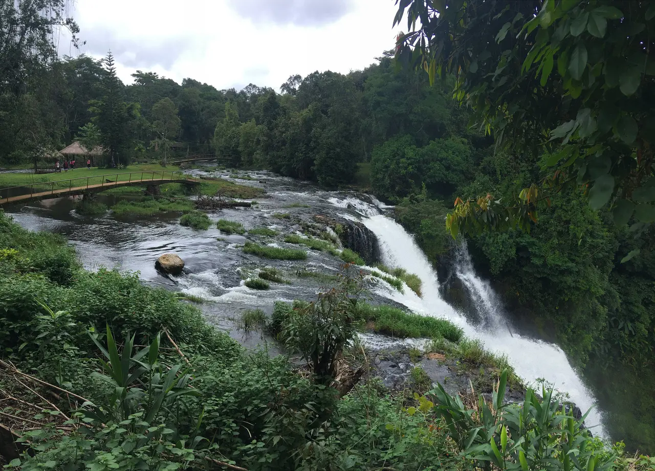 Tad Yuang waterfall spilling over a rock ledge into forest on the Bolaven Plateau