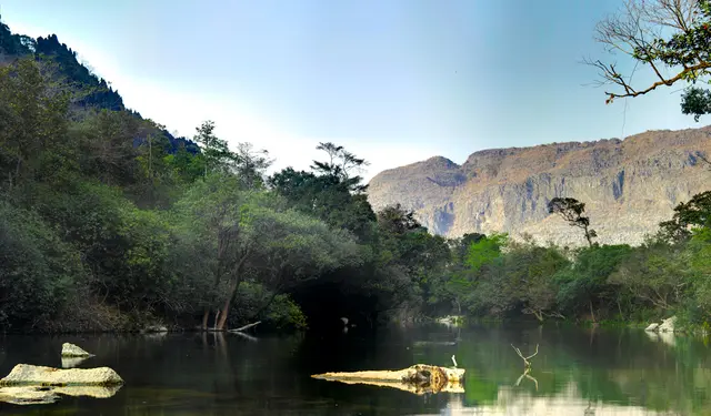A calm green river pool below limestone cliffs at Tha Falang near Thakhek