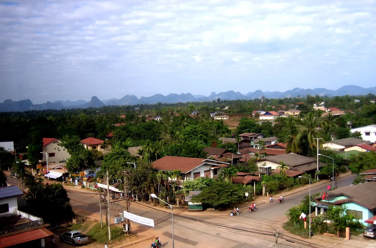 Rooftops and trees of Thakhek town with a line of limestone mountains on the horizon