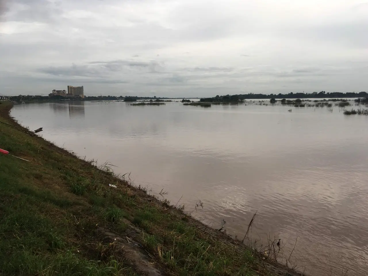 The broad Mekong at Vientiane under a grey sky, with Thailand on the far bank